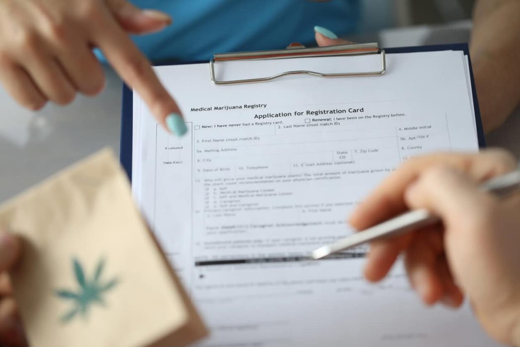 Patient filling application for registration card Focus on female hand holding paper folder and pointing for text. Sick patient with paper package with cannabis symbol on it and signing document. Healthcare and medical marijuana concept
