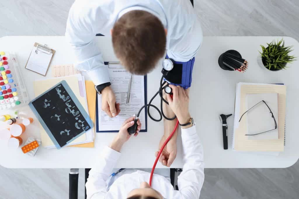 Doctor measuring pressure on patients shoulder top view