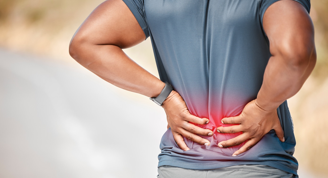 Shot of an unrecognizable man standing alone outside and suffering from backache during his run
